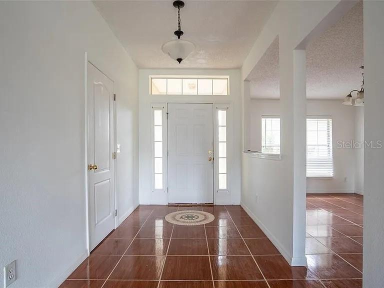 entryway featuring dark tile patterned flooring and a textured ceiling