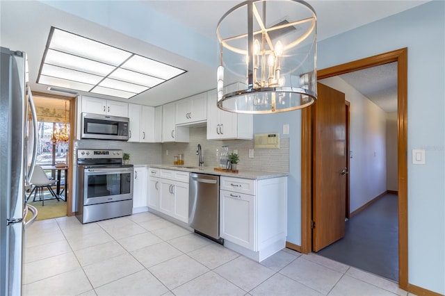 kitchen with white cabinetry, pendant lighting, stainless steel appliances, and backsplash