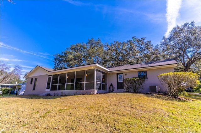 view of front of house with central AC unit, a sunroom, and a front yard