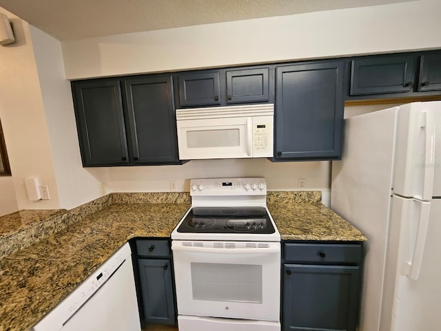 kitchen featuring dark stone countertops and white appliances