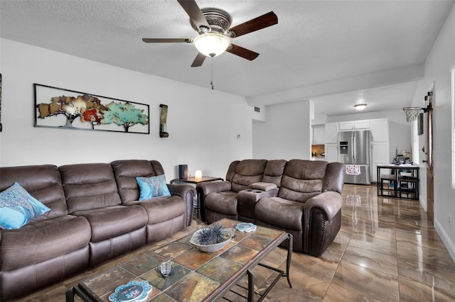 living room featuring ceiling fan and a textured ceiling