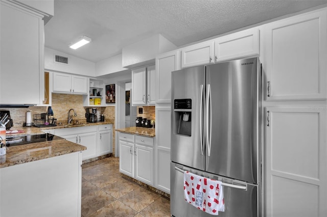 kitchen featuring white cabinetry, stainless steel fridge, light stone counters, and backsplash