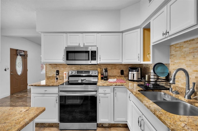 kitchen featuring sink, stainless steel appliances, light stone counters, white cabinets, and decorative backsplash