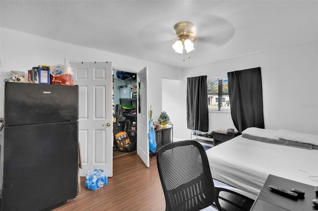 bedroom featuring black refrigerator, hardwood / wood-style floors, a textured ceiling, and ceiling fan