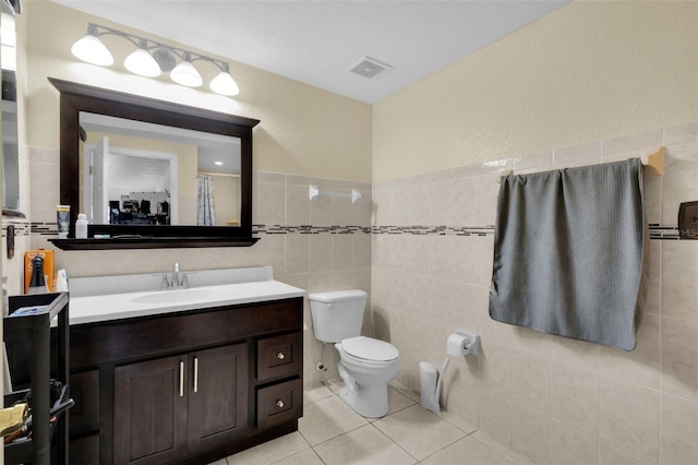 bathroom with tile patterned floors, vanity, toilet, and tile walls