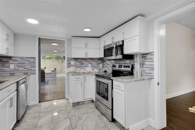 kitchen featuring light stone counters, stainless steel appliances, and white cabinets