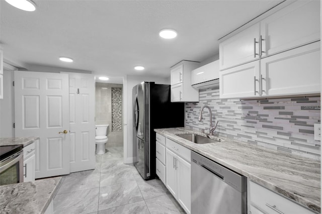 kitchen featuring sink, white cabinetry, stainless steel appliances, tasteful backsplash, and light stone countertops