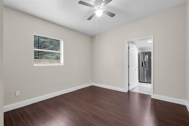 empty room with a textured ceiling, dark hardwood / wood-style floors, and ceiling fan