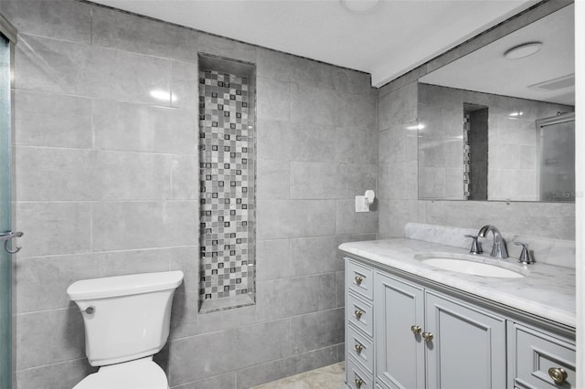 bathroom with tile walls, vanity, and toilet