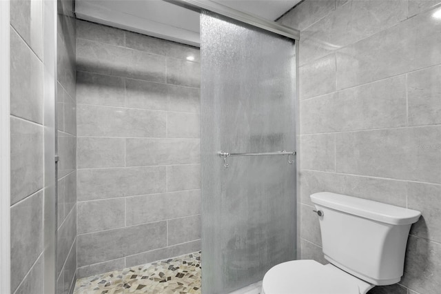 bathroom featuring tile walls, toilet, and walk in shower