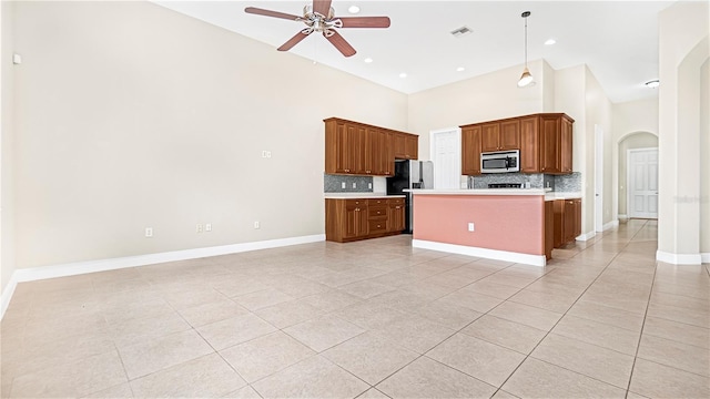 kitchen with stainless steel appliances, hanging light fixtures, a center island, and backsplash