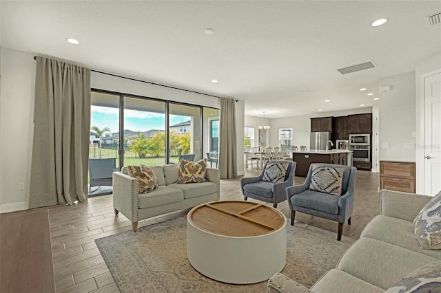 living room with an inviting chandelier, a wealth of natural light, and light hardwood / wood-style floors