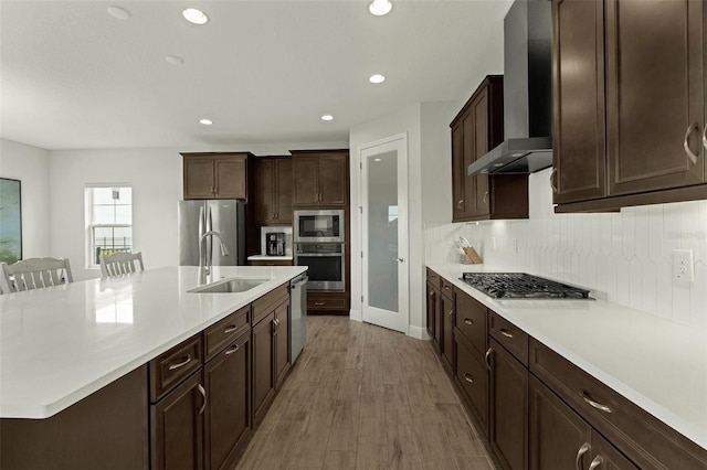 kitchen with sink, stainless steel appliances, a kitchen breakfast bar, tasteful backsplash, and wall chimney exhaust hood