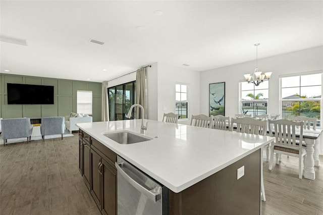 kitchen with dark brown cabinetry, sink, hanging light fixtures, dishwasher, and a kitchen island with sink