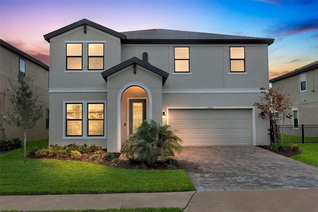 traditional-style home featuring an attached garage, fence, decorative driveway, and stucco siding