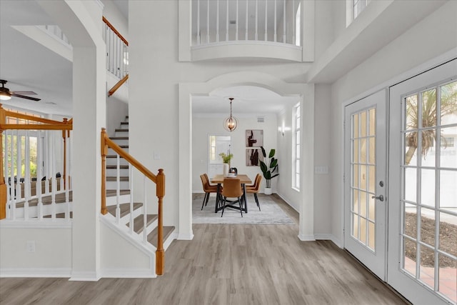 foyer featuring crown molding, a towering ceiling, plenty of natural light, and light hardwood / wood-style floors