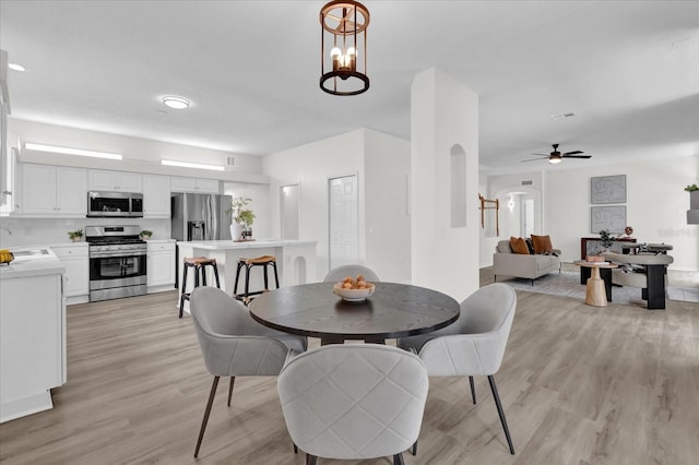 dining space with sink, light hardwood / wood-style floors, and ceiling fan