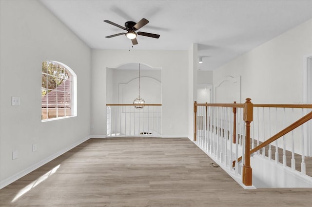 spare room with ceiling fan with notable chandelier and light hardwood / wood-style flooring