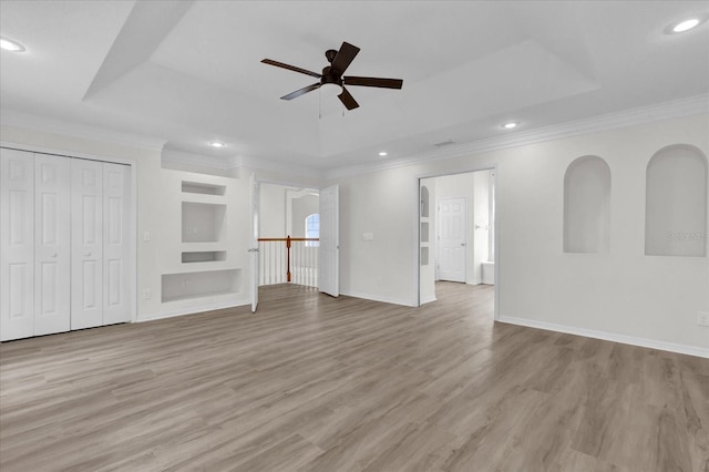 unfurnished living room featuring crown molding, light hardwood / wood-style floors, a raised ceiling, and ceiling fan