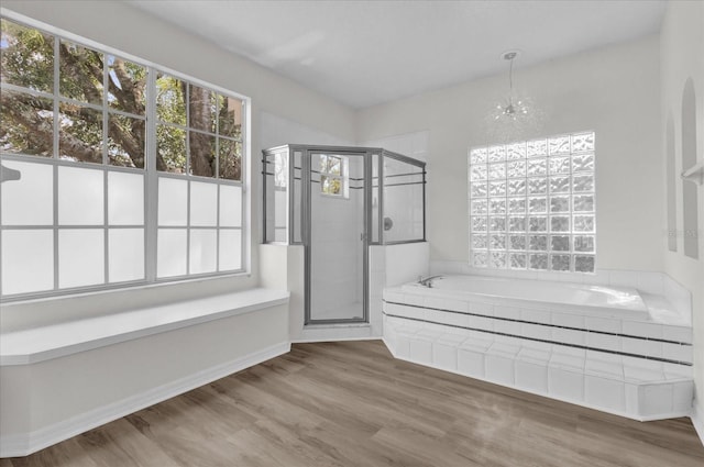 bathroom with an inviting chandelier, hardwood / wood-style floors, and plus walk in shower