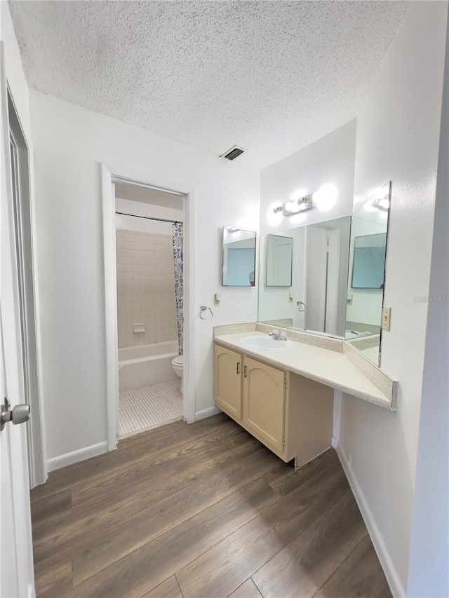 full bathroom featuring vanity, hardwood / wood-style flooring, a textured ceiling, and shower / bath combo with shower curtain