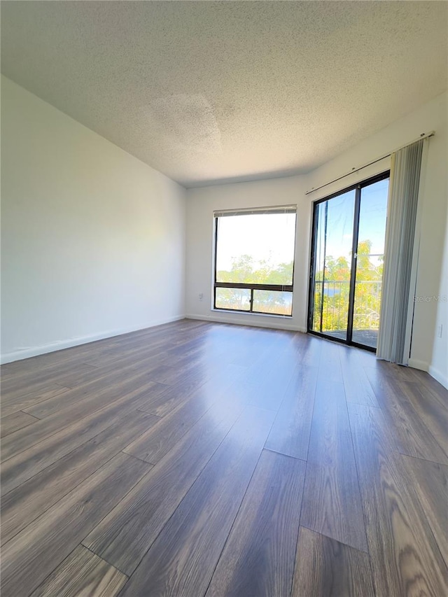 empty room with dark wood-type flooring and a textured ceiling