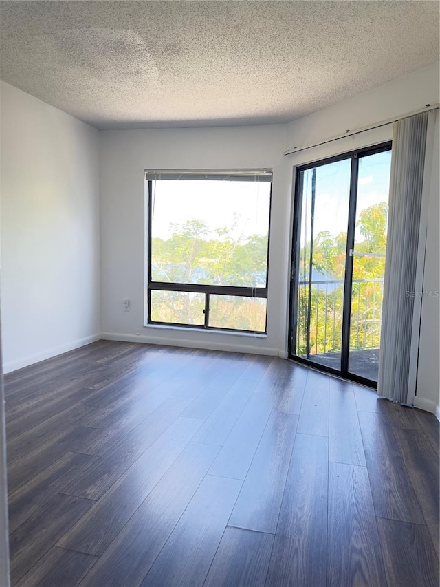 spare room featuring dark hardwood / wood-style floors and a textured ceiling