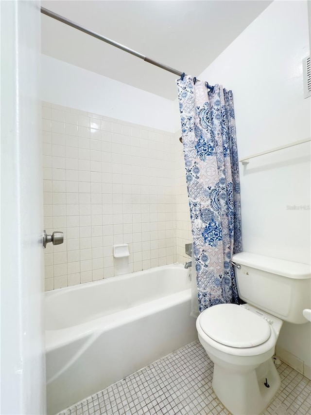 bathroom with shower / tub combo with curtain, tile patterned floors, and toilet