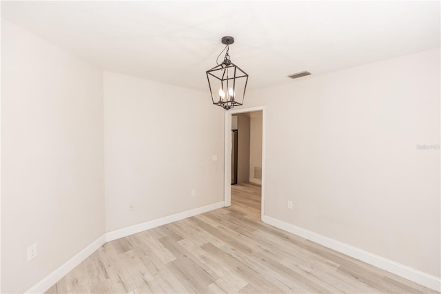 unfurnished room with a chandelier and light wood-type flooring