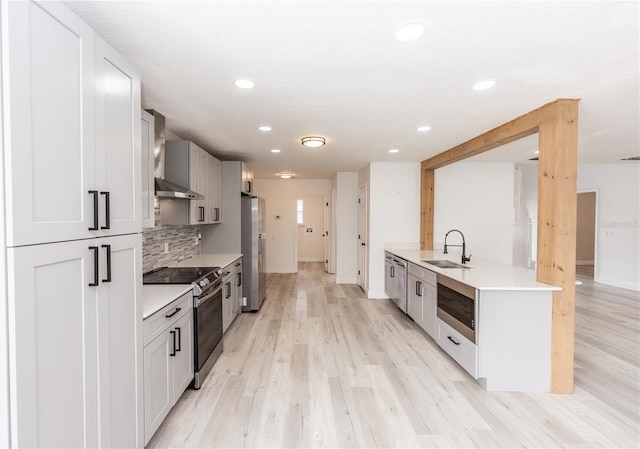 kitchen with sink, decorative backsplash, kitchen peninsula, stainless steel appliances, and light hardwood / wood-style flooring