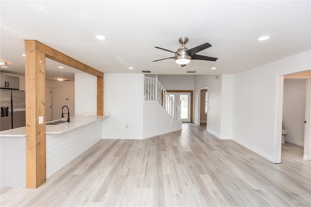 unfurnished living room featuring ceiling fan, sink, and light hardwood / wood-style floors