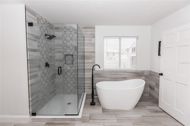 bathroom featuring tile walls and separate shower and tub