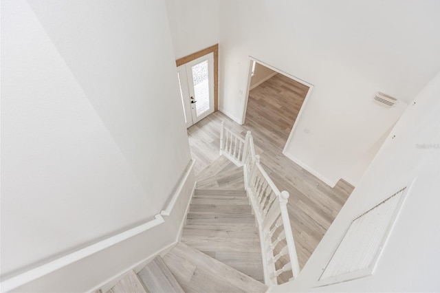 stairway featuring wood-type flooring and a high ceiling