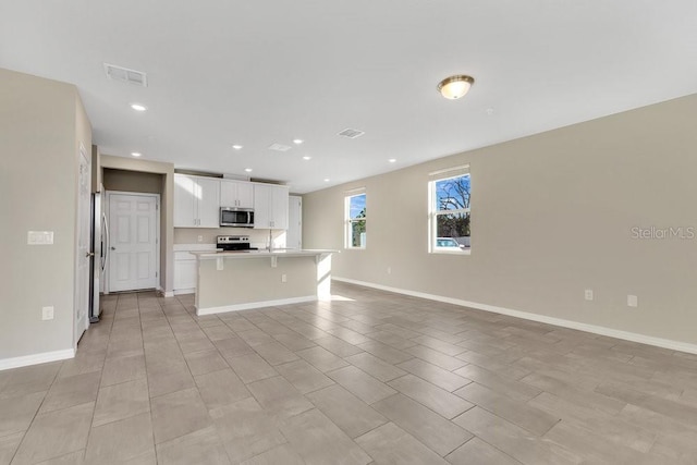 kitchen featuring a kitchen bar, a center island with sink, white cabinets, and appliances with stainless steel finishes