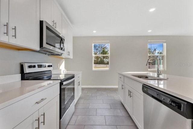 kitchen featuring stainless steel appliances, white cabinetry, sink, and light tile patterned floors