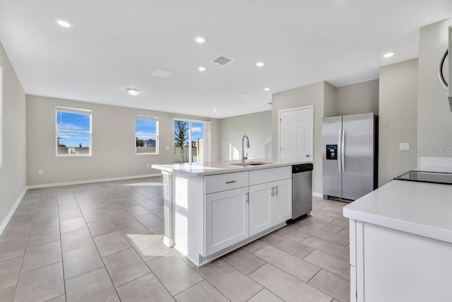 kitchen with stainless steel appliances, sink, white cabinetry, a center island with sink, and a healthy amount of sunlight