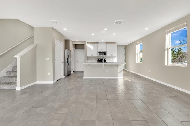 kitchen featuring stainless steel appliances, a center island with sink, and white cabinets