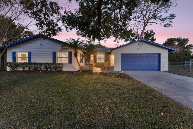 single story home featuring a garage and a lawn