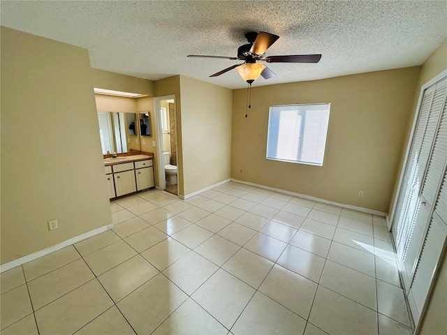 unfurnished bedroom featuring light tile patterned floors, a textured ceiling, baseboards, and a closet