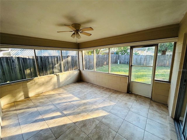 unfurnished sunroom featuring a ceiling fan and a wealth of natural light