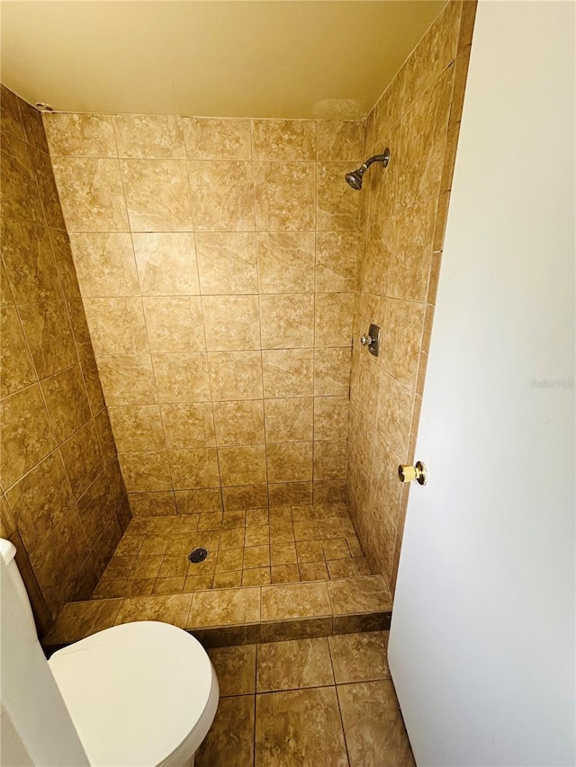 bathroom featuring tiled shower and toilet