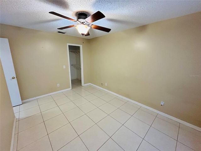 empty room with light tile patterned floors, a textured ceiling, and ceiling fan