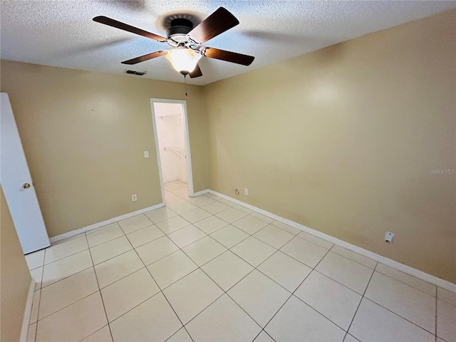 unfurnished room with ceiling fan, light tile patterned floors, and a textured ceiling