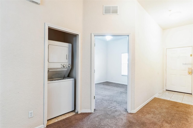 laundry area with light colored carpet and stacked washer / dryer