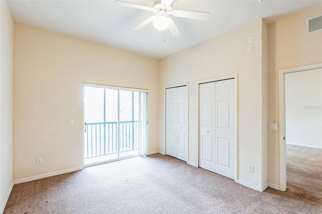 unfurnished bedroom featuring access to exterior, carpet floors, multiple closets, and ceiling fan