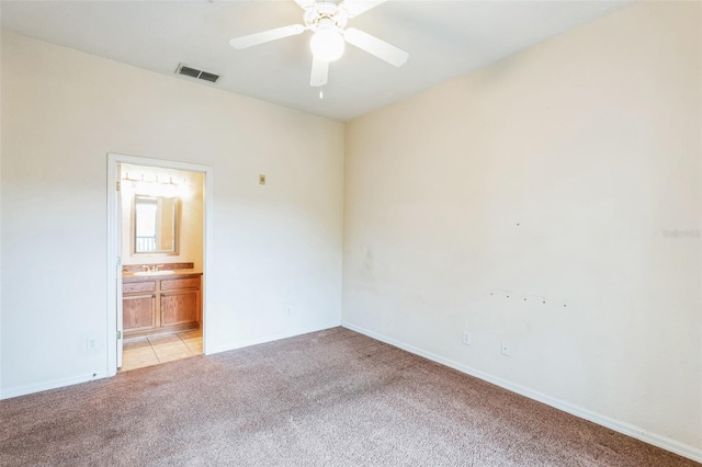 interior space featuring connected bathroom, sink, light carpet, and ceiling fan