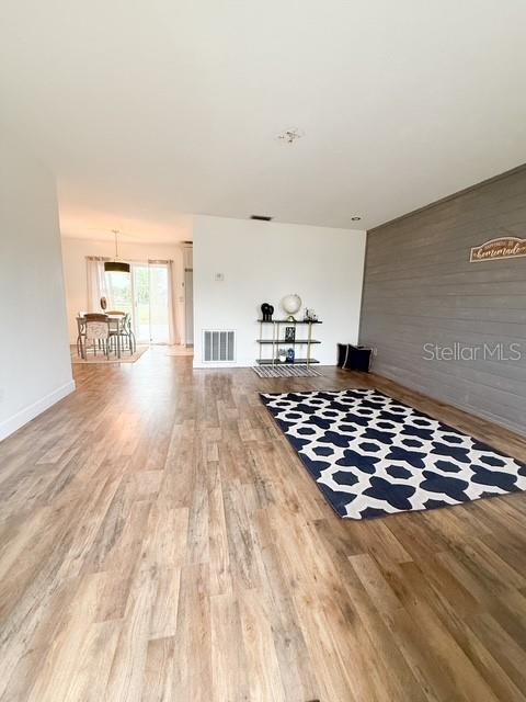 unfurnished living room featuring wood-type flooring and wooden walls