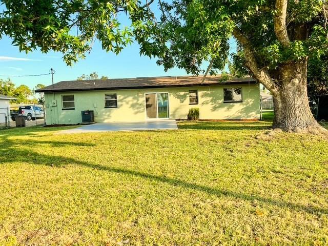 back of property with cooling unit, a yard, and a patio area