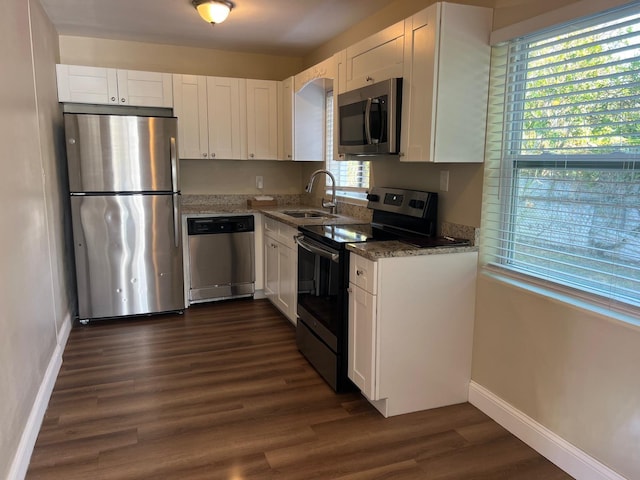 kitchen featuring dark stone countertops, stainless steel appliances, sink, and white cabinets