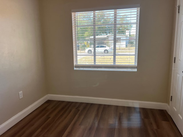 spare room with dark hardwood / wood-style flooring and a wealth of natural light